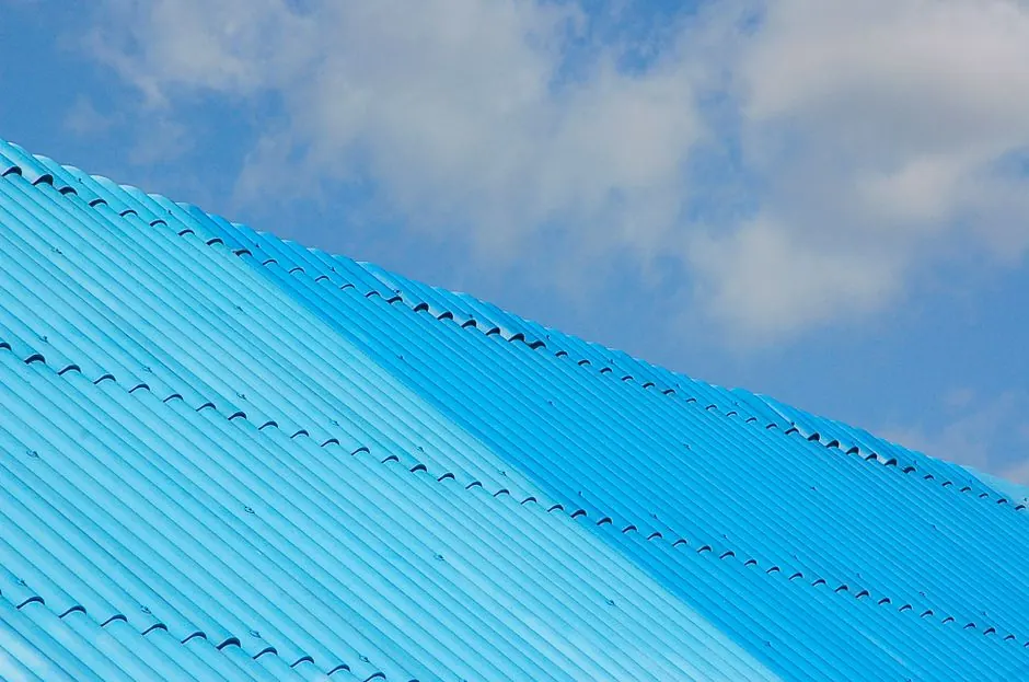 A bright blue corrugated roof shot from a low angle against a clear sky.