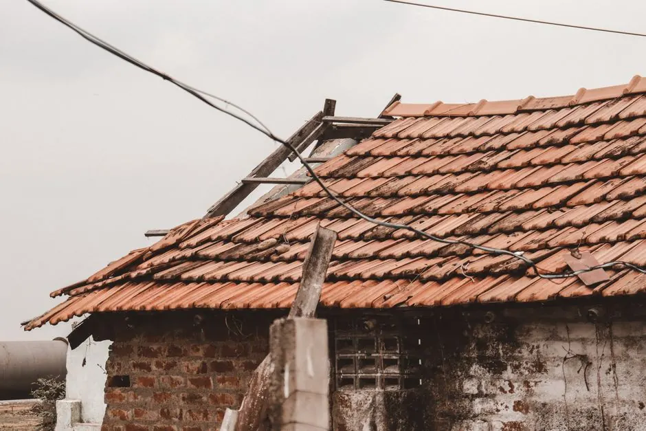 An old rural house with a damaged clay tile roof in Chennai, India, showing signs of decay.