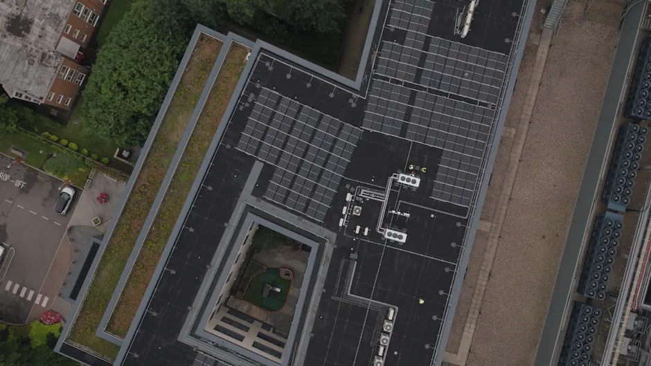 High-angle view of urban rooftop featuring solar panels and greenery.